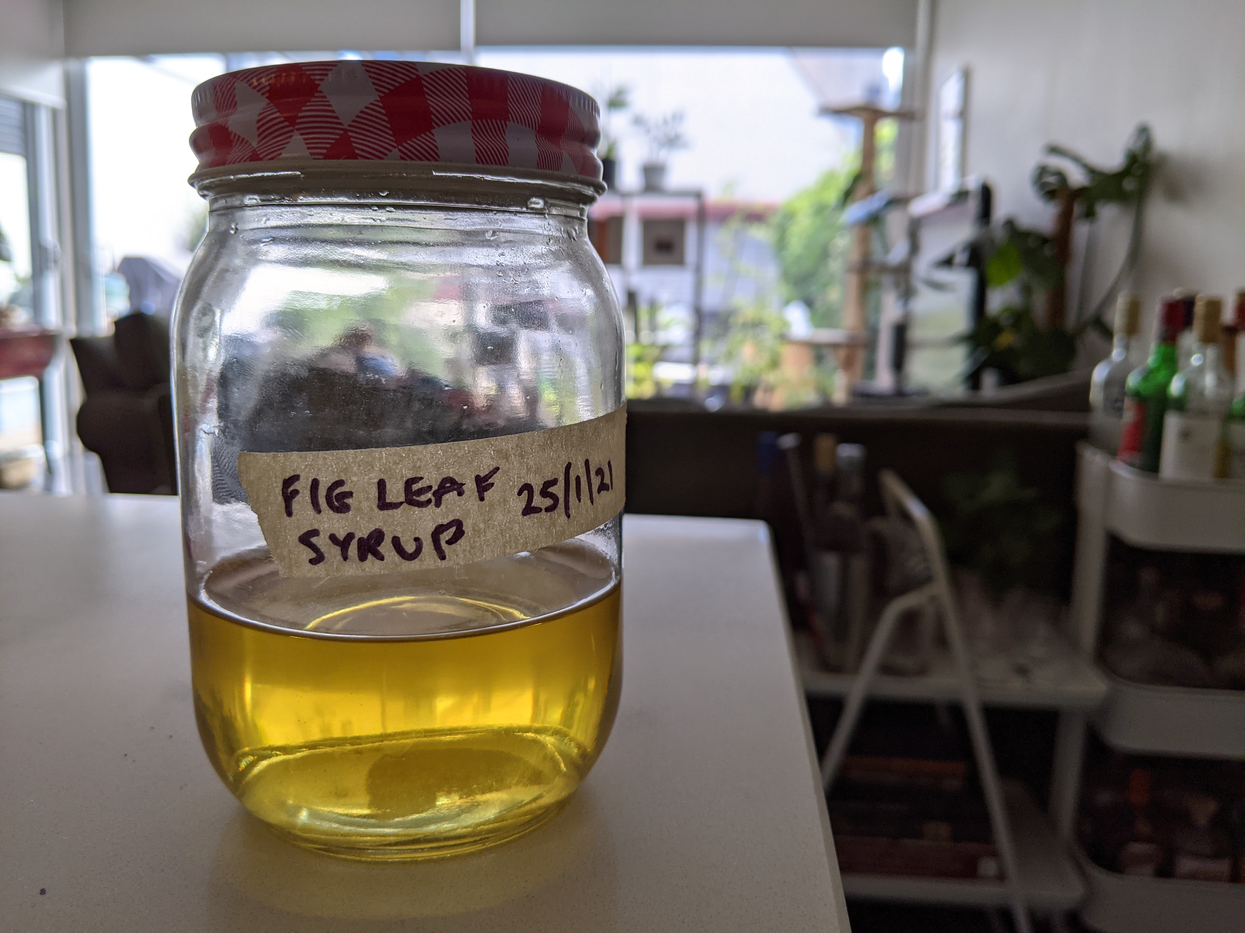 A small jar with a yellow-colored syrup in it, sitting on a stone countertop
