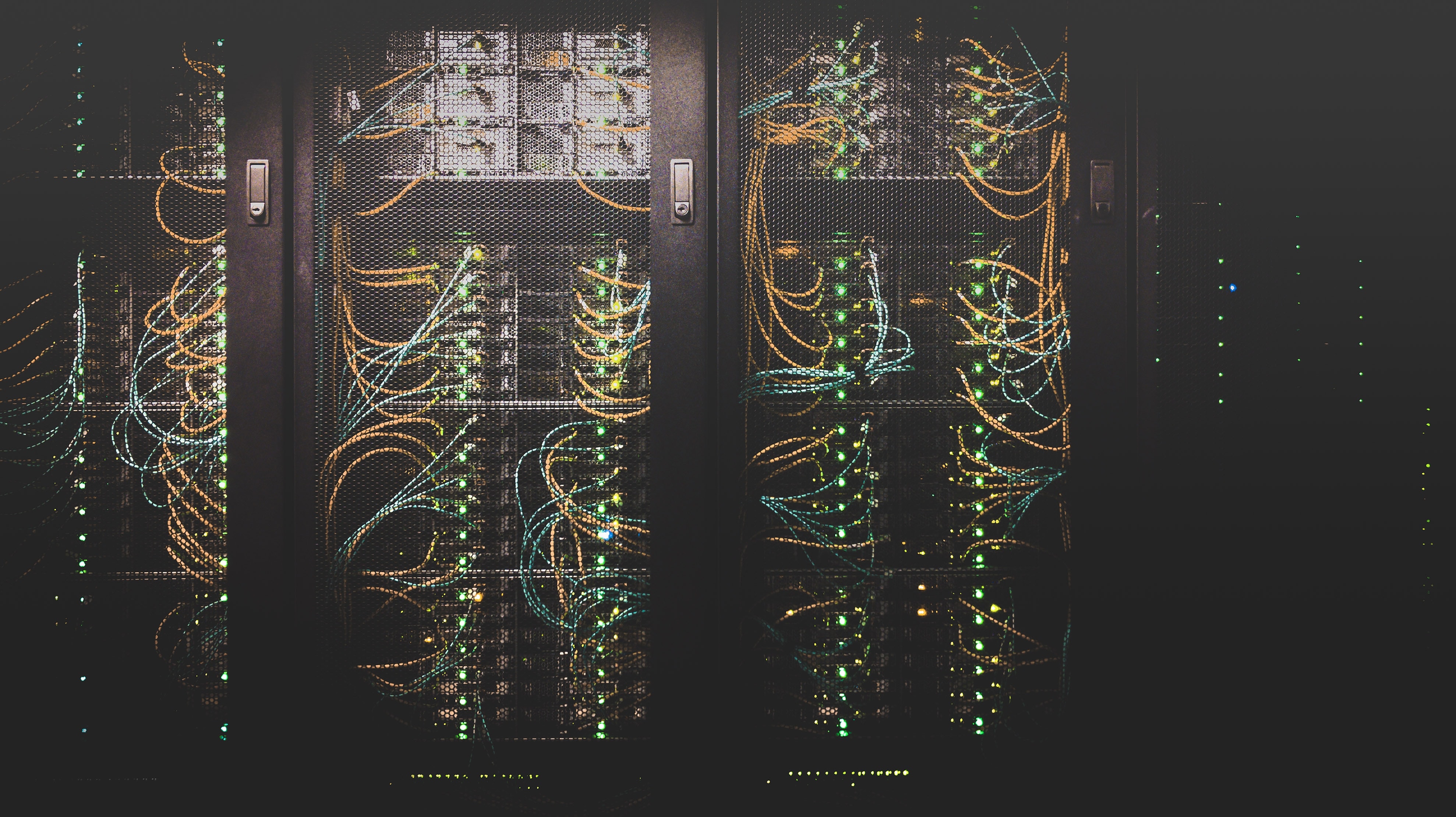 An image of a server rack, with the mesh doors closed. Many colored ethernet cables connect different components.